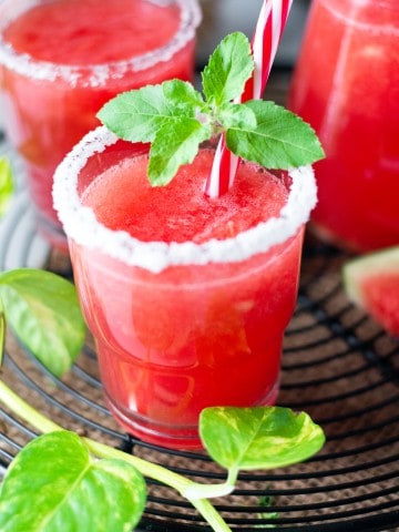 Up close shot of glass filled with watermelon margarita on black cooling rack.