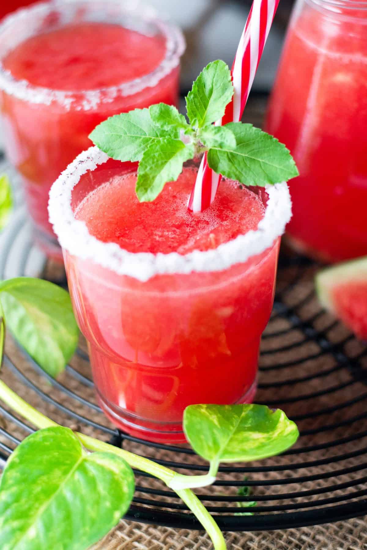 Up close shot of glass filled with watermelon margarita on black cooling rack.