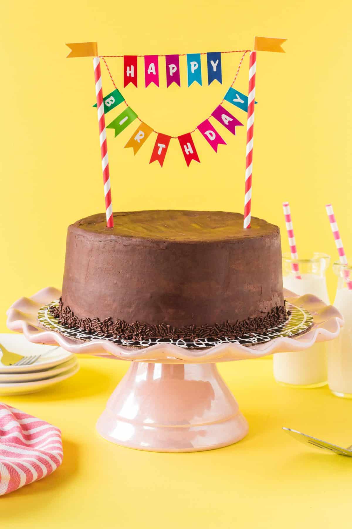 chocolate frosted marble cake on pink cake plate with happy birthday banner