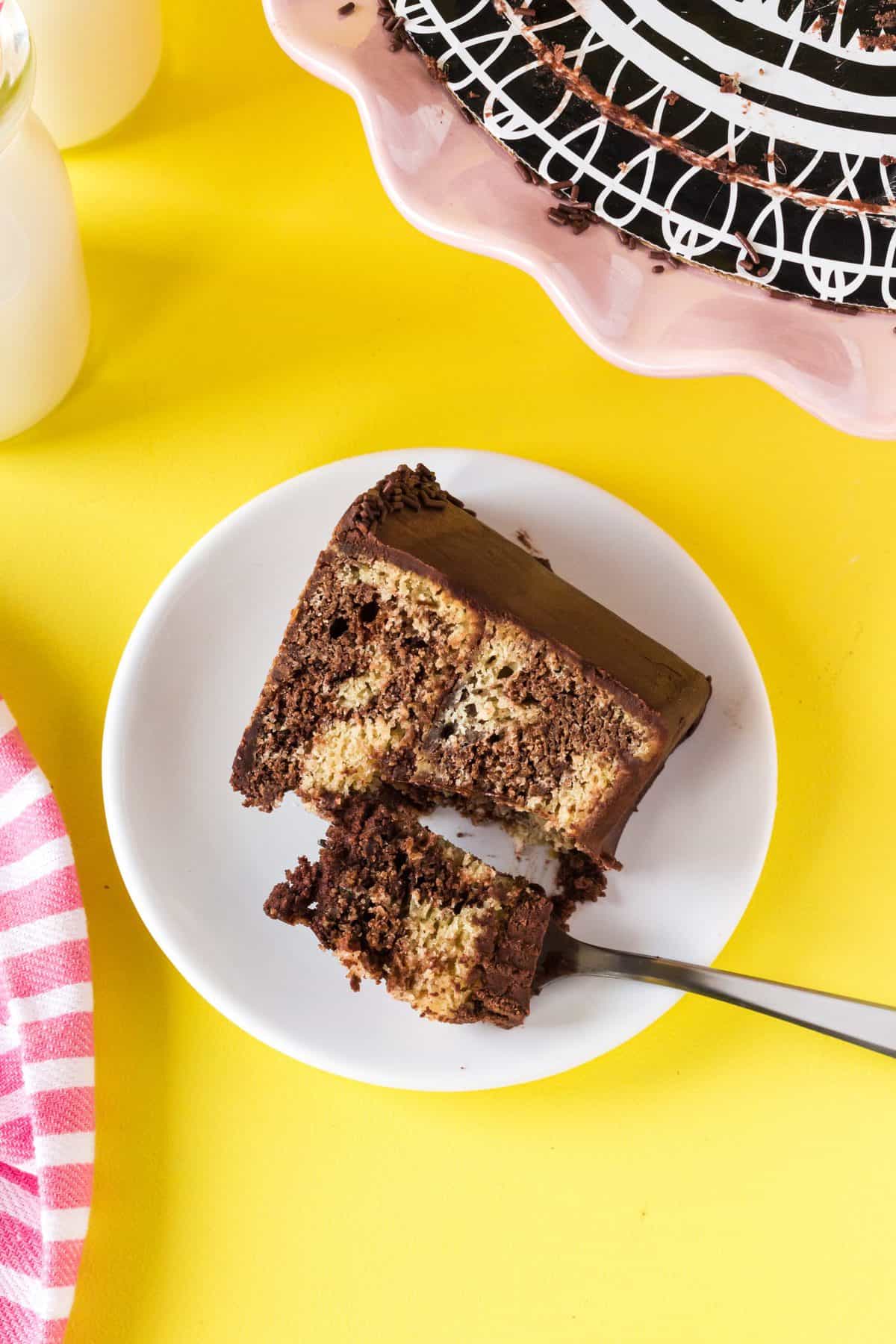 a fork taking a bite of a slice of marble cake on yellow background