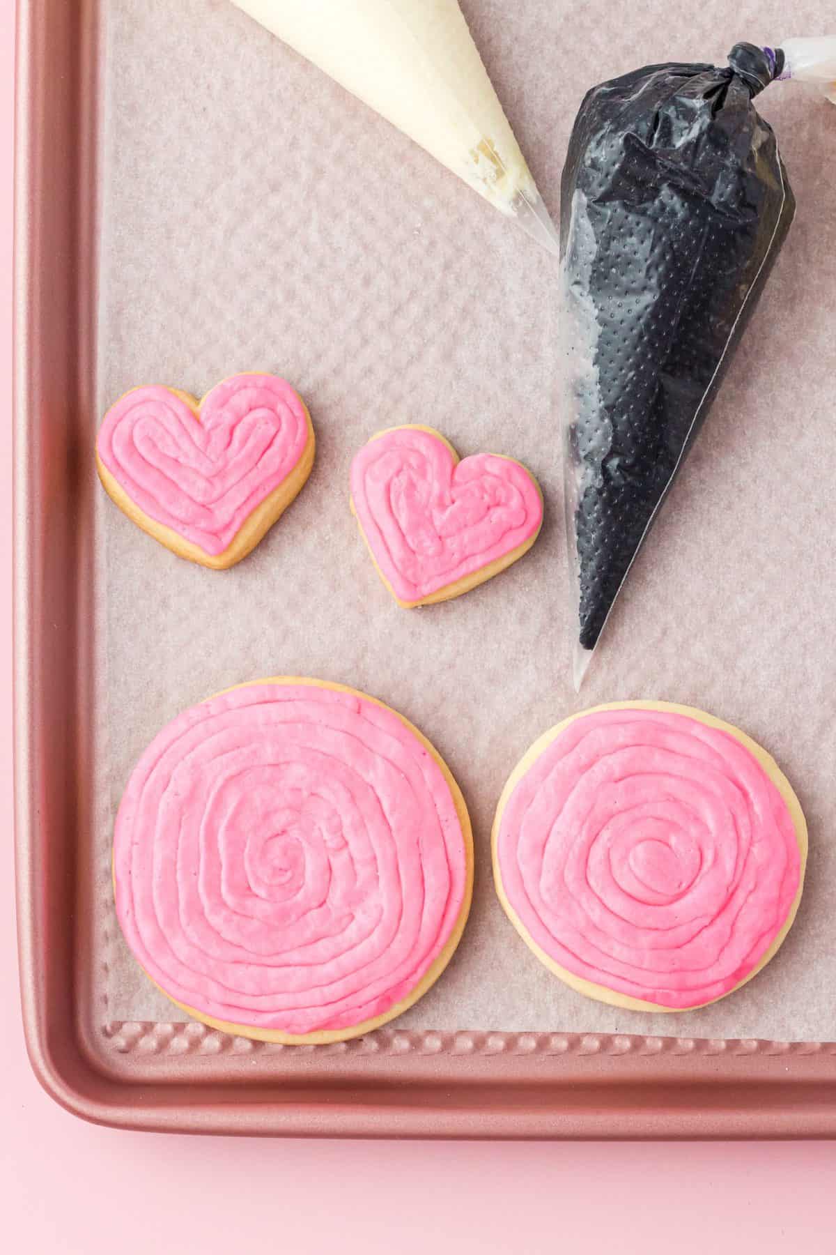 metal tray with round sugar cookies that are frosting with pint frosting 