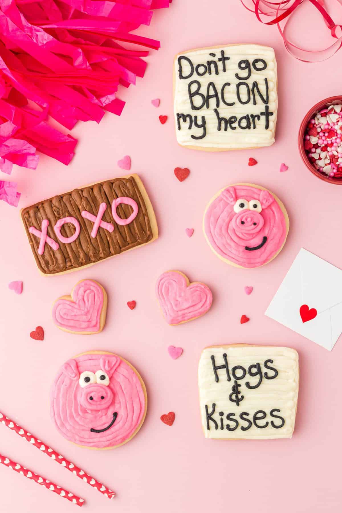 pig valentine sugar cookies with notes on a pink background