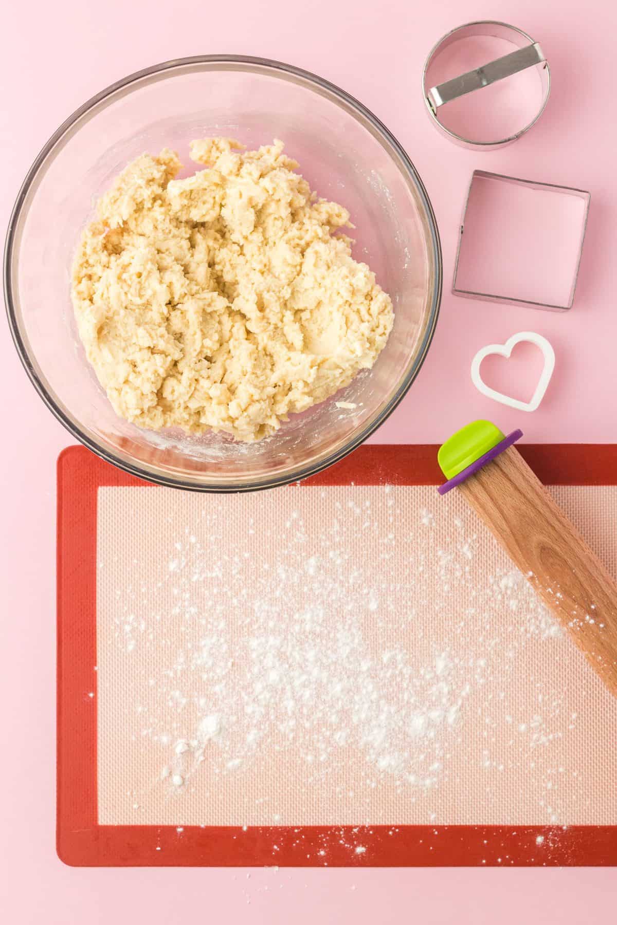 sprinkling flour on surface to roll out sugar cookie dough