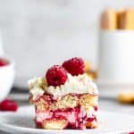 slice of raspberry amaretto tiramisu on white plate with metal background