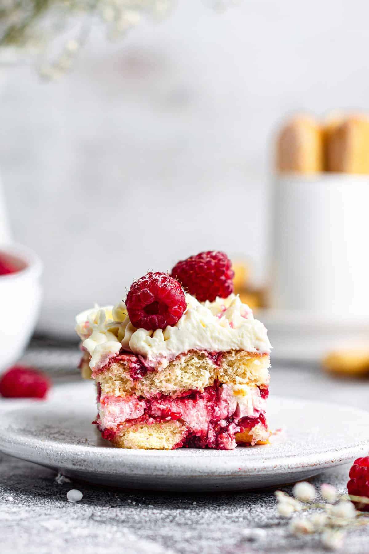 slice of raspberry amaretto tiramisu on white plate with metal background