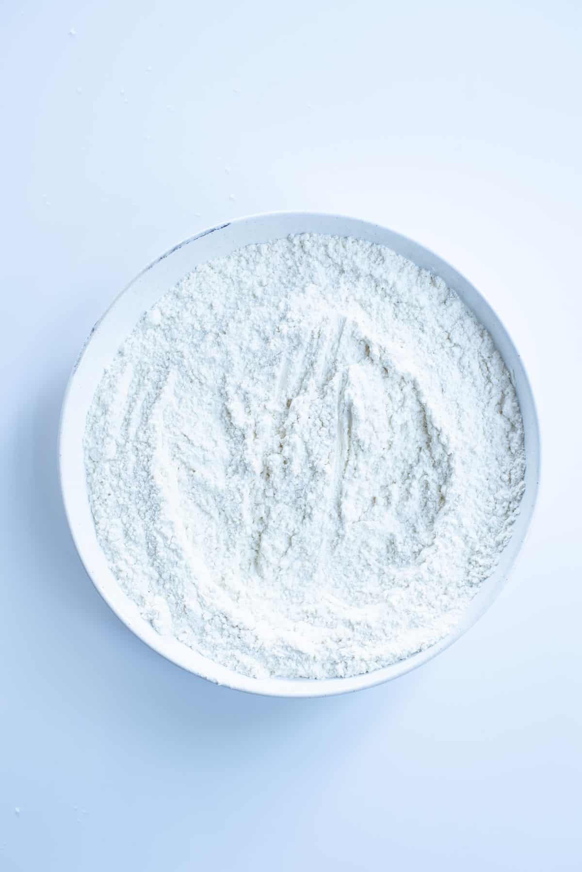 the dry flour mixture in large white bowl on white background. 