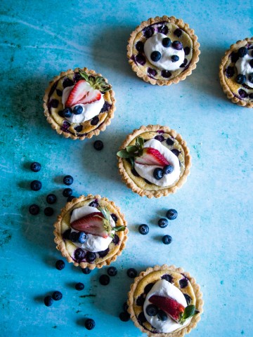 overhead shot of mini fruit tarts on blue background.