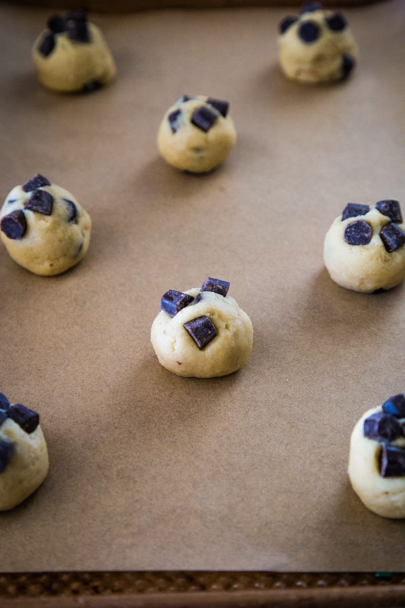 Rolling out the cookie dough and adding chocolate chunks to the tops before baking.