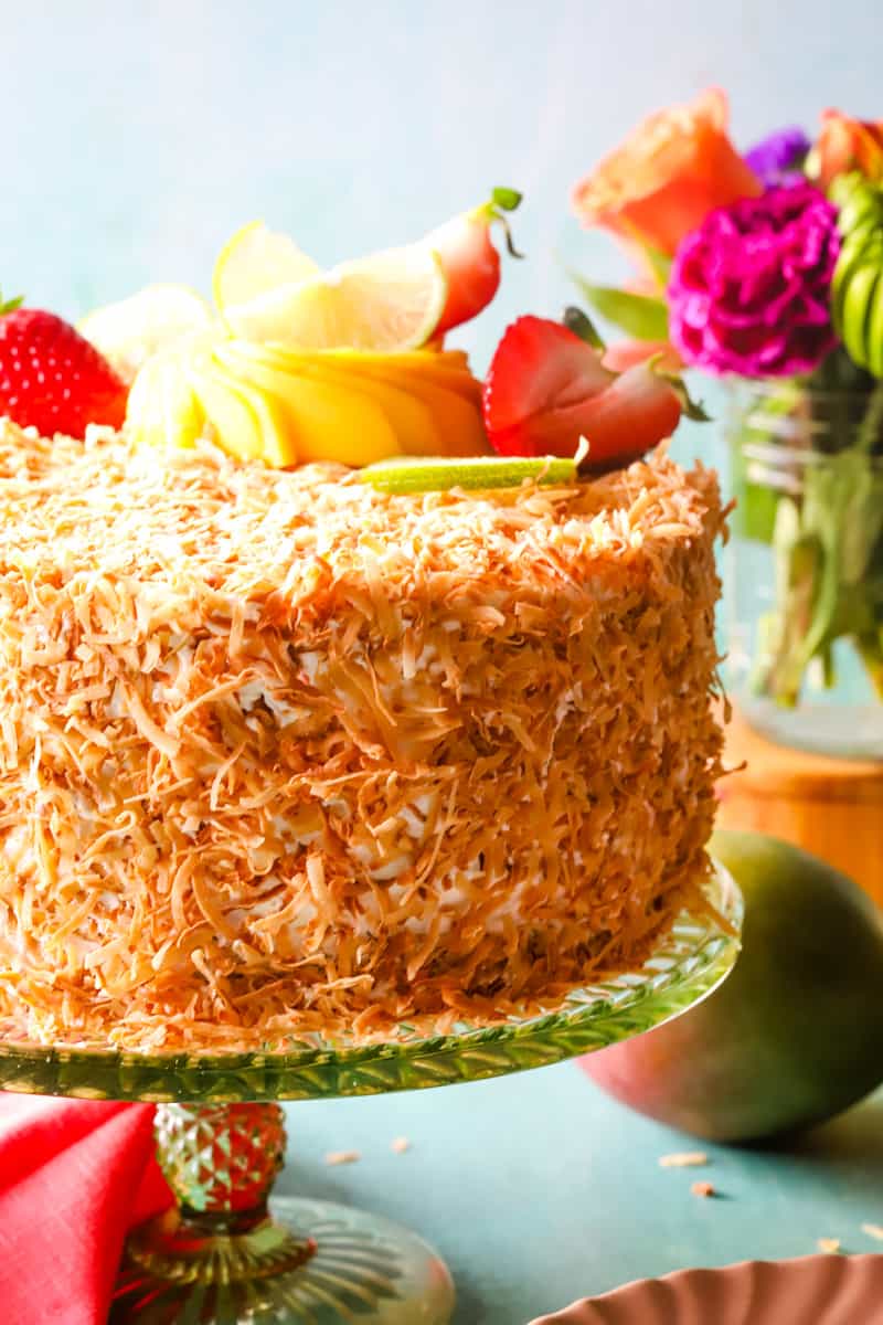 Up close photo of coconut mango curd cake on green cake stand. 