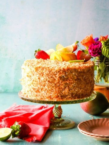 cake covered in toasted coconut on a green cake plate.