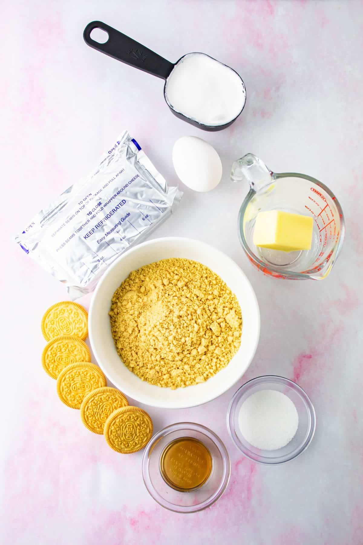 Ingredients to make golden Oreo cheesecake bars on white background.