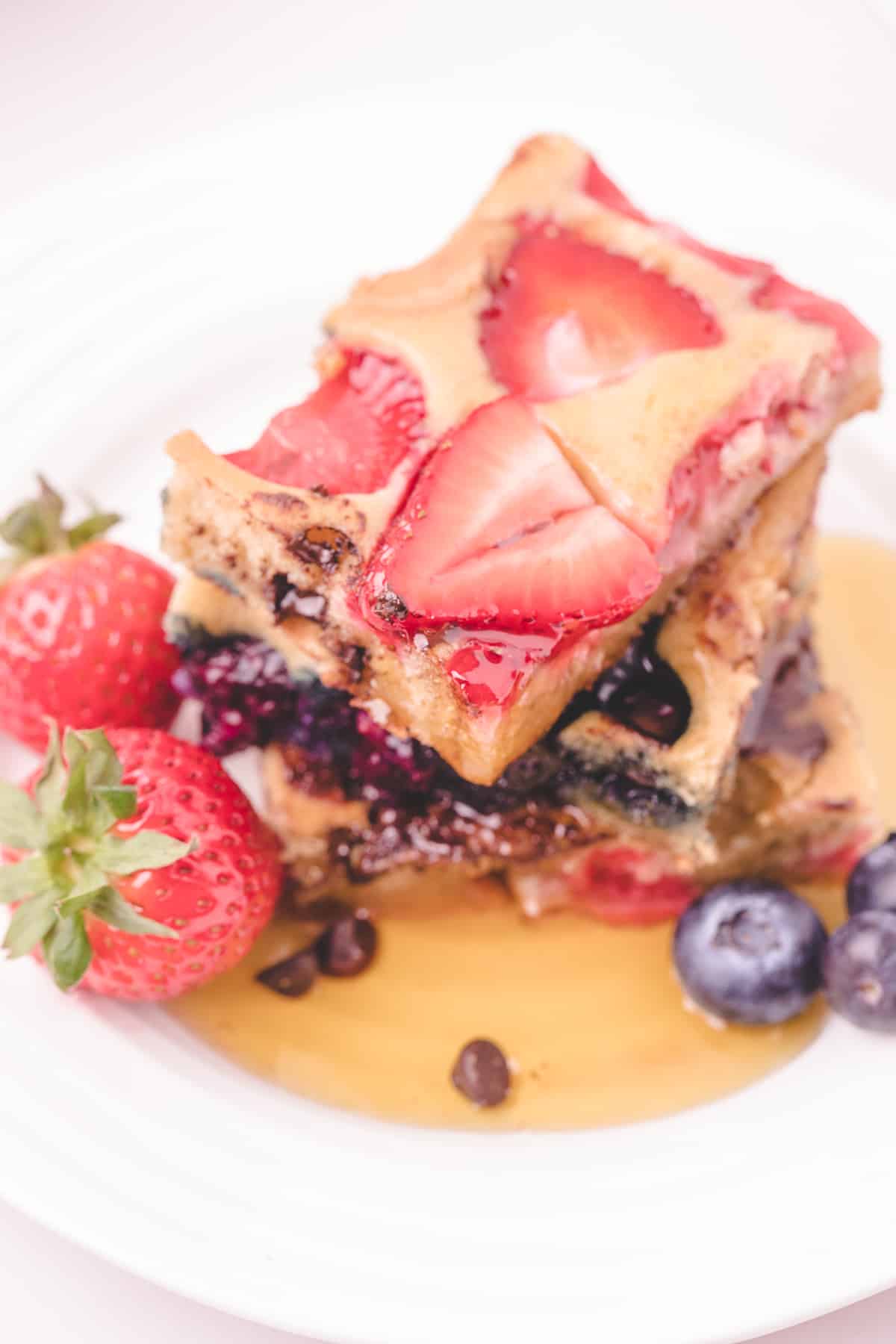 Stack of 3 berry topped pancake squares with syrup. 