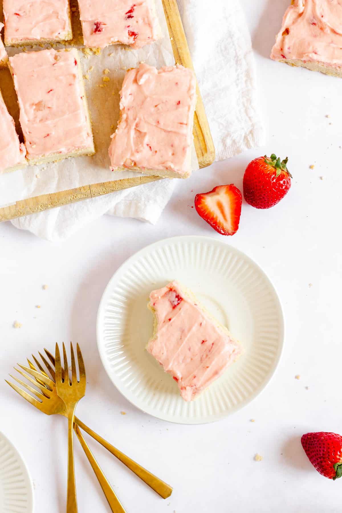 White plate with strawberry sugar cookie bar and fresh strawberries.
