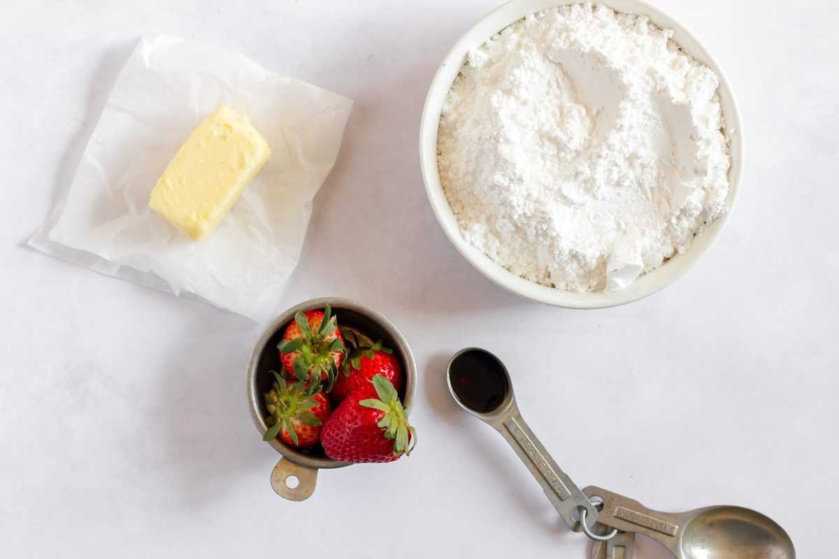 ingredients to make the strawberry frosting in white bowls. 