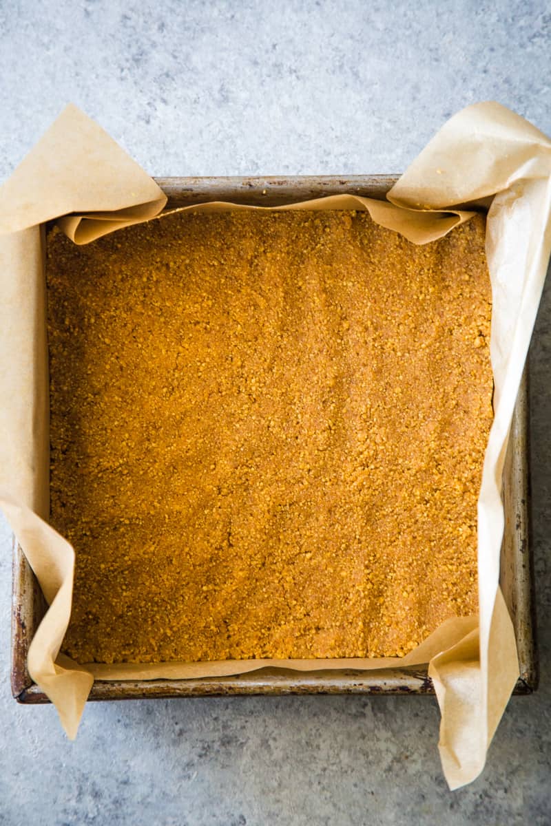Graham cracker crust pressed into a pan lined with parchment. 