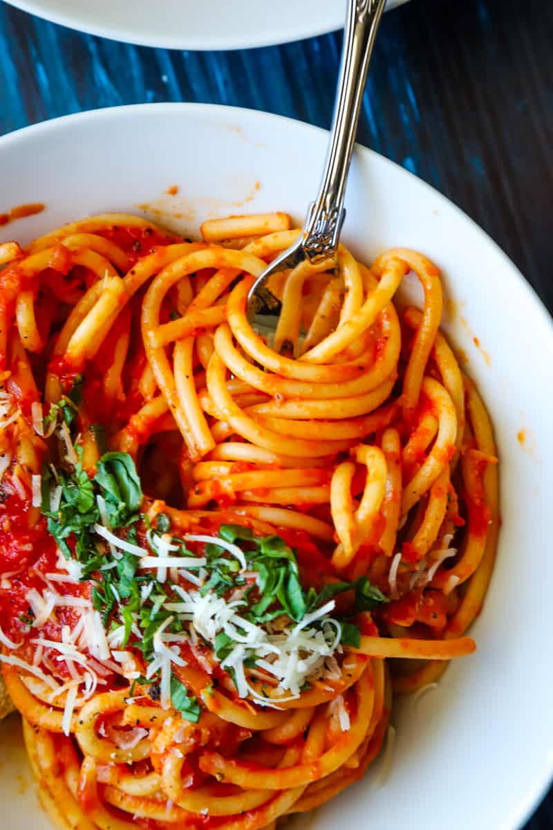 Up close photo of for twirling spaghetti in white bowl. 