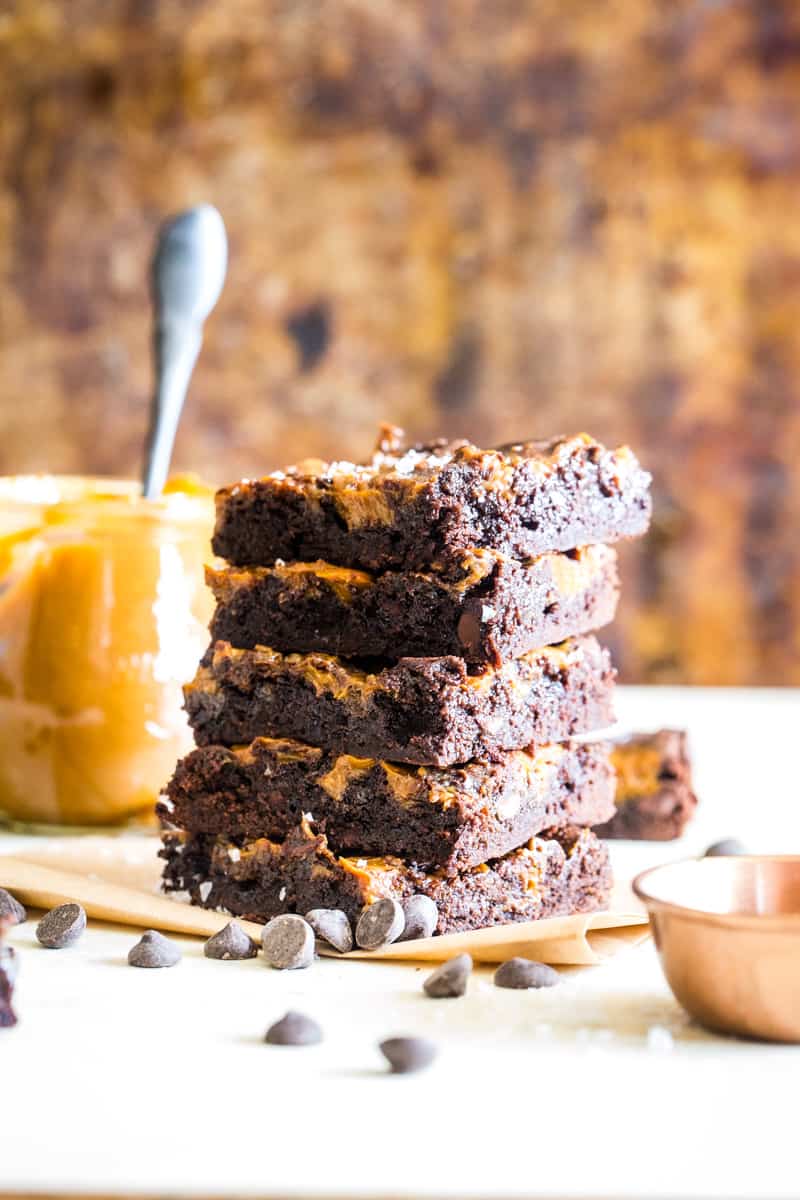 jar of dulce de leche next to 5 stacked brownies. 