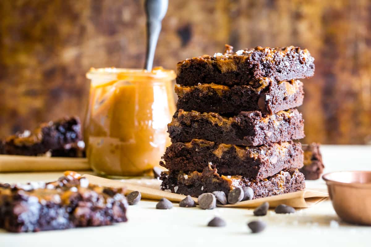 stack of brownies with jar of caramel in background