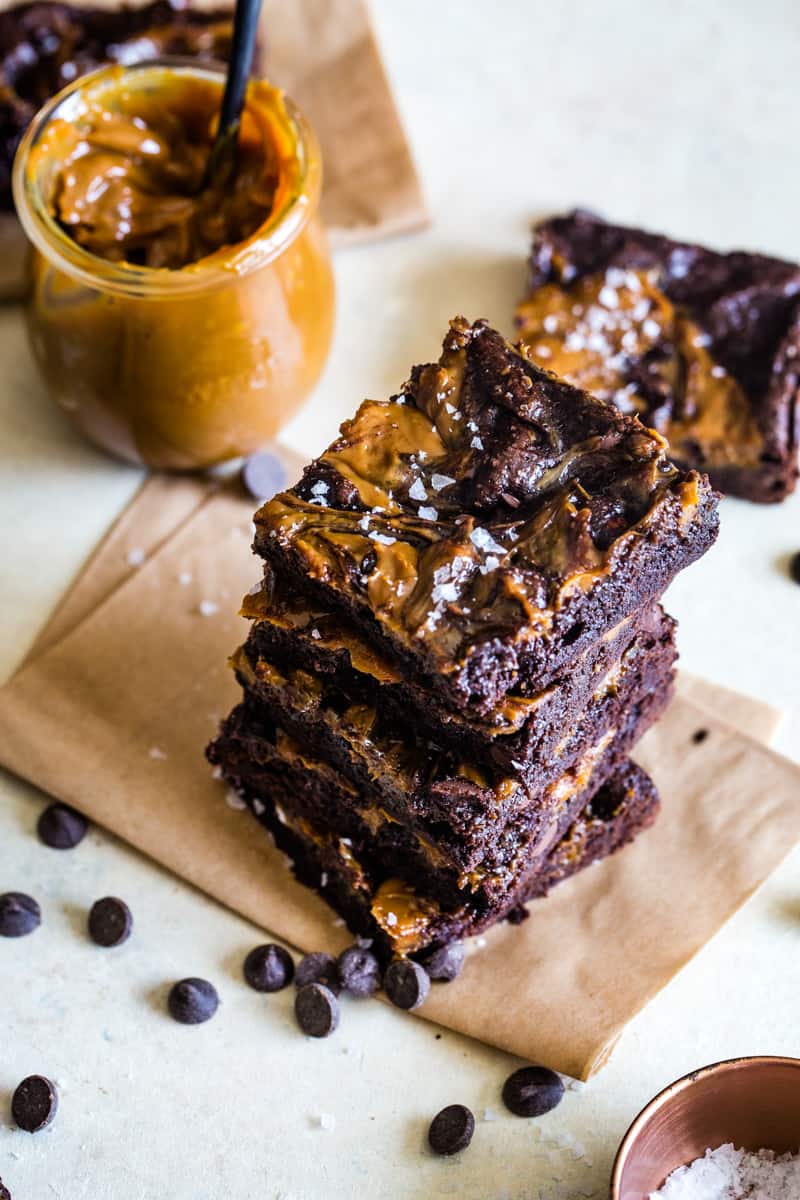 brownie squares stacked on a piece of brown parchment paper. 