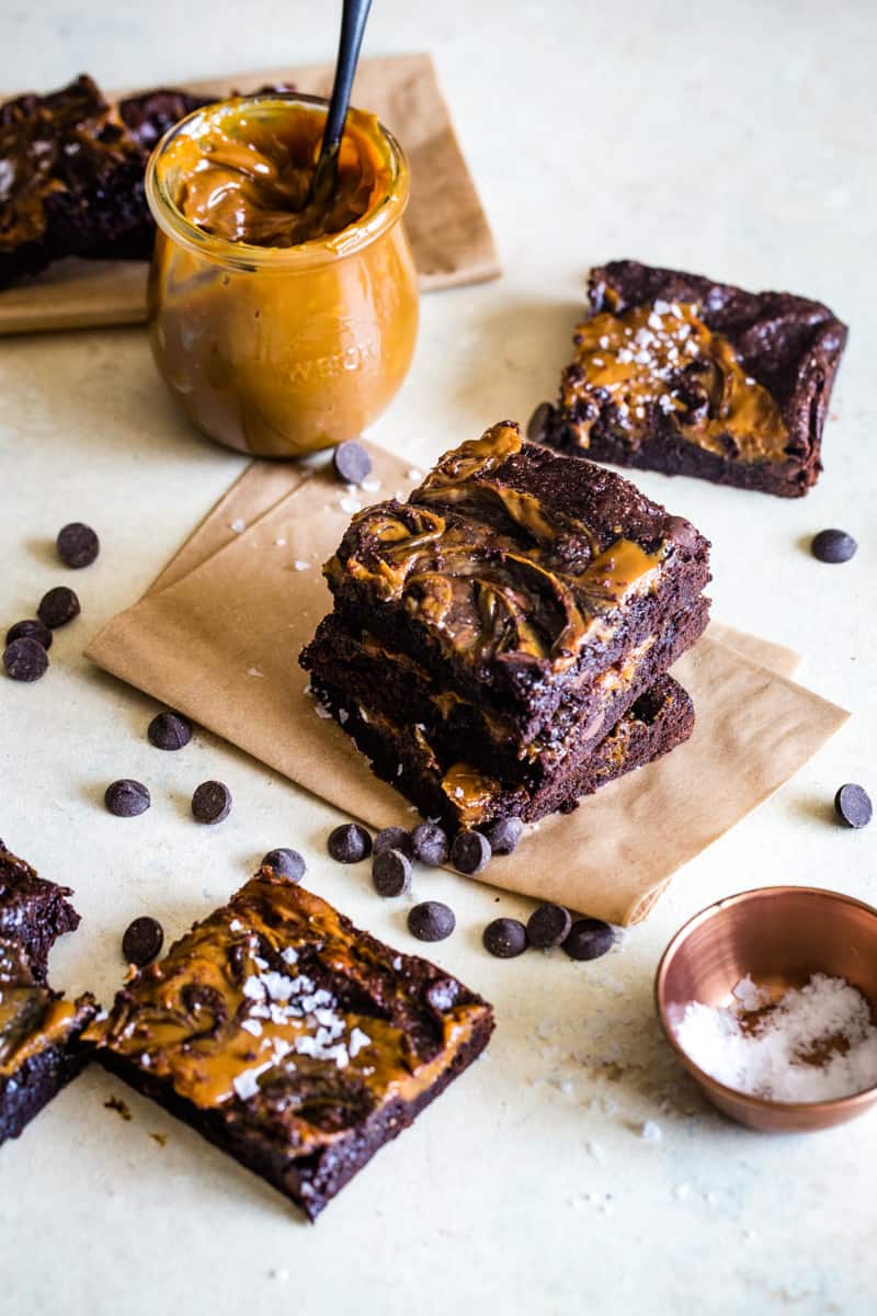stacked brownies with a jar of dulce de leche next to them. 
