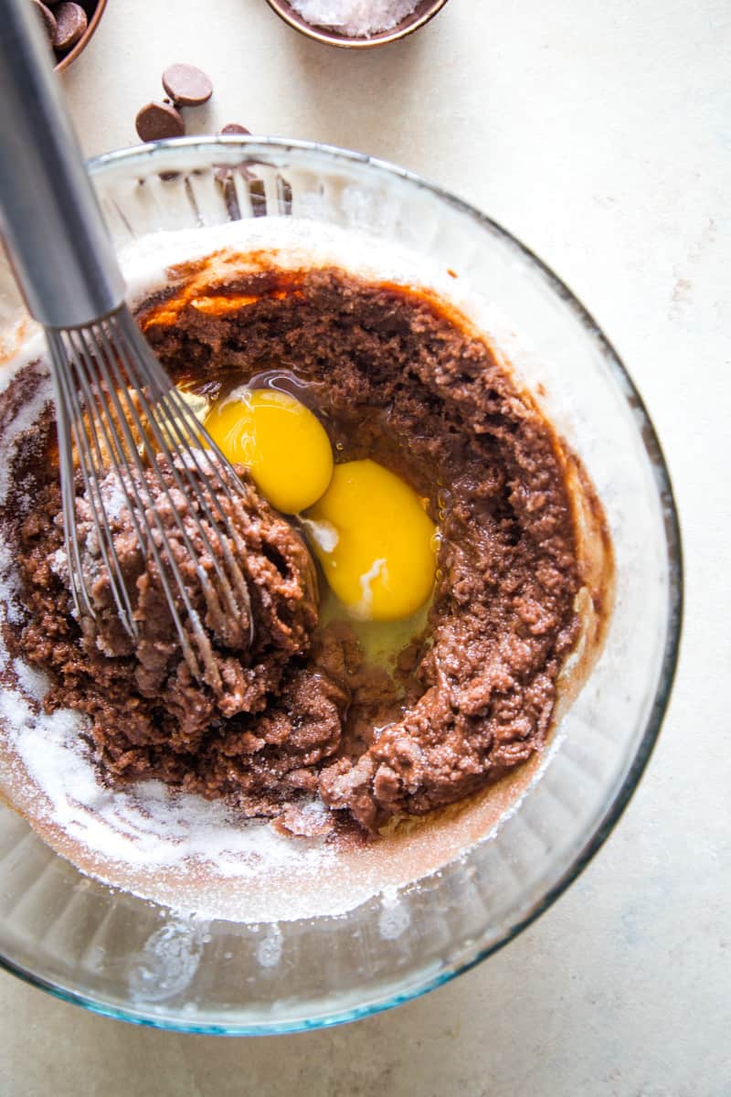 Adding eggs to chocolate butter mixture in large glass bowl. 