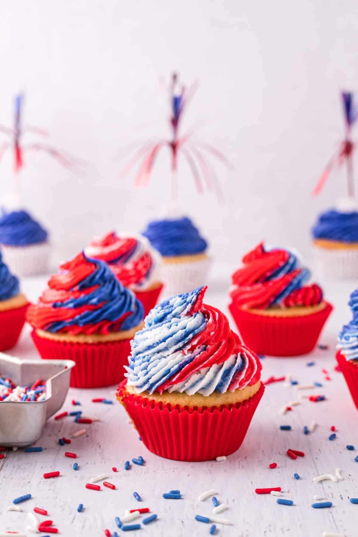 Cupcakes in red liners with red, white and blue frosting on white background. 
