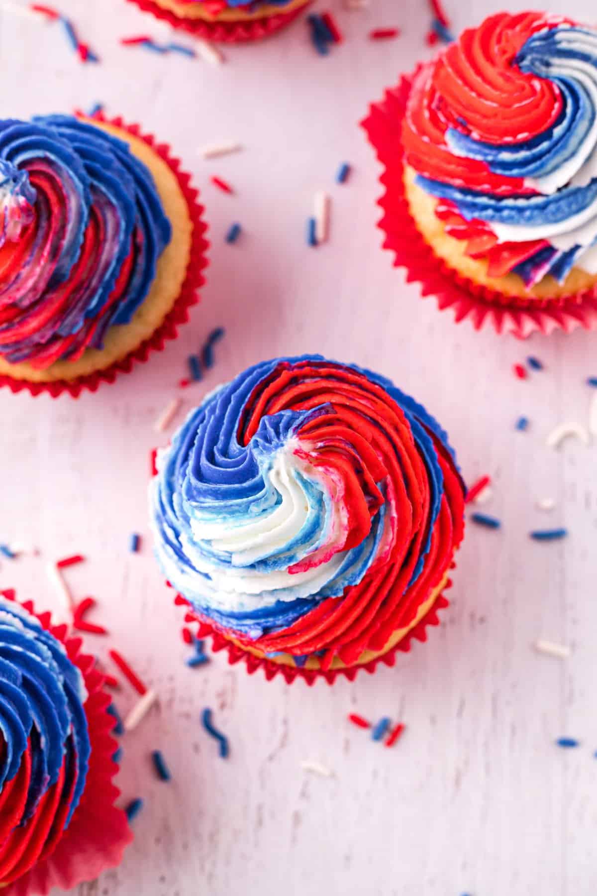 Overhead shot of tie dye red white and blue frosted cupcakes. 