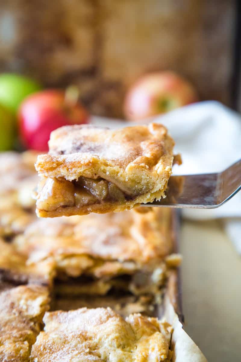 Pie knife taking a square of apple pie bars from pan. 