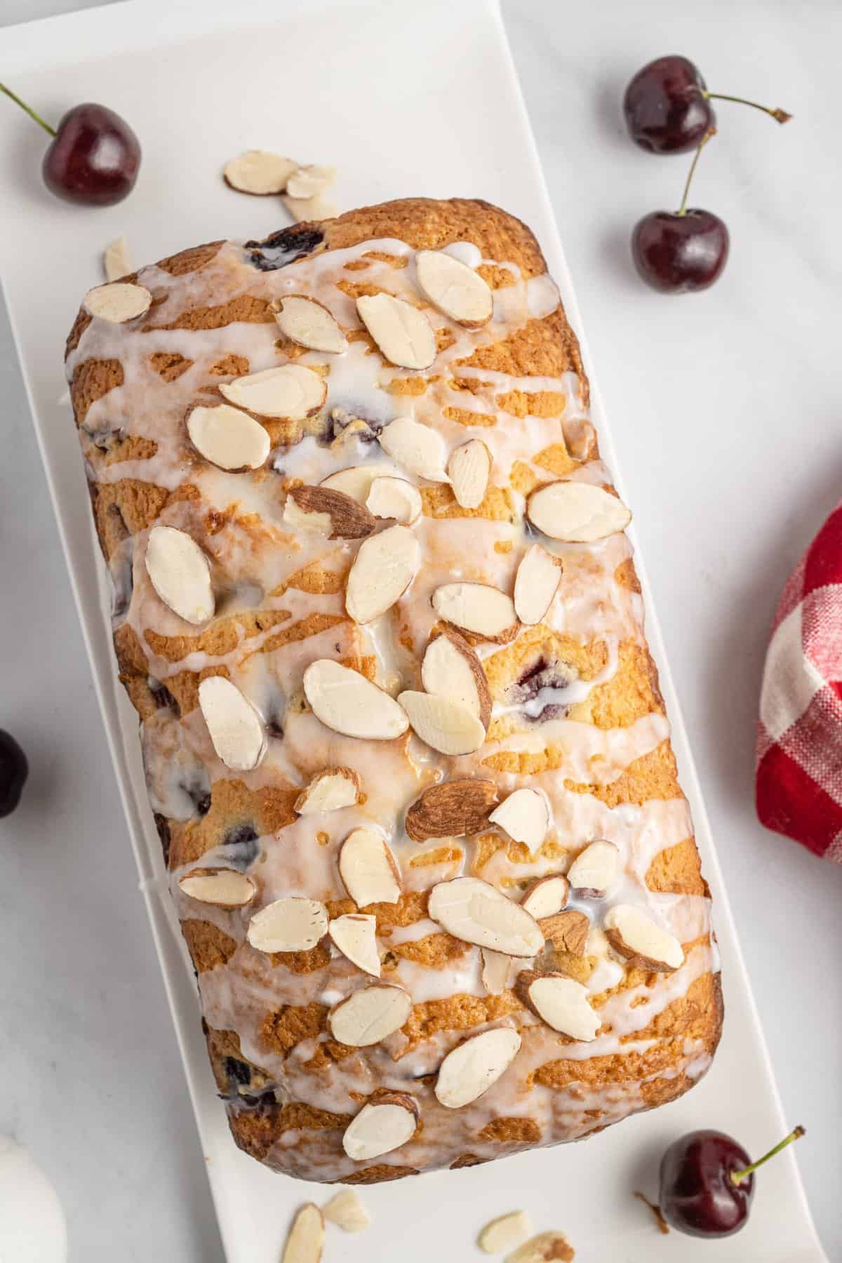 Overhead shot of cherry bread topped with glaze and sliced almonds.