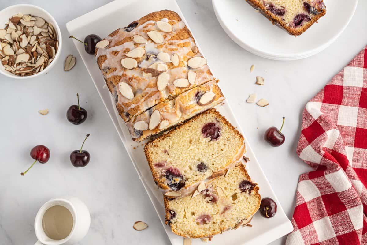 Overhead shot of cherry almond bread on white plate and sliced.