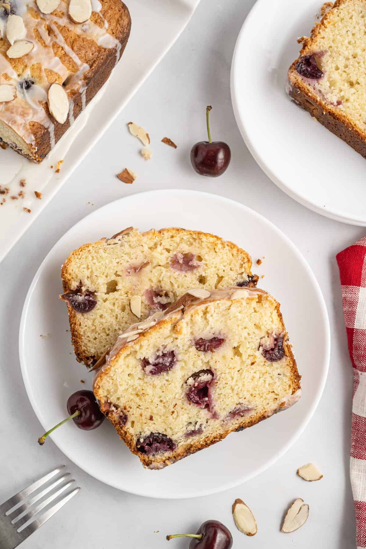 Two slices of cherry bread on white plate with red and white dishtowel next to it.