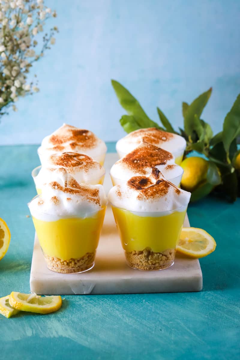 lemon meringue pudding cups on white cutting board and teal background. 