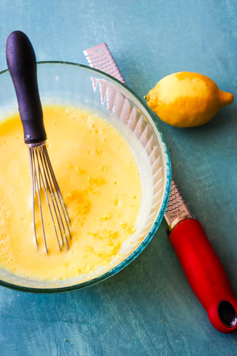 Making the lemon pudding in glass bowl with lemon peeler next to it.