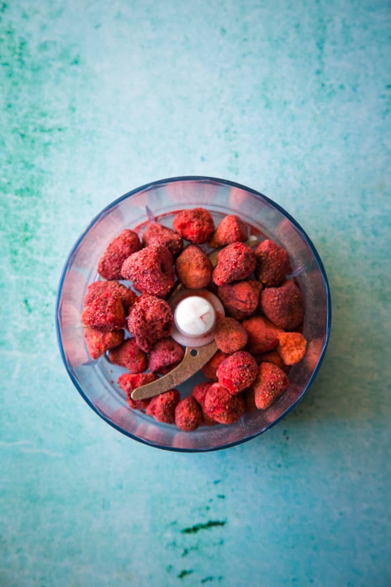 Freeze dried strawberries in a food processor on blue background. 