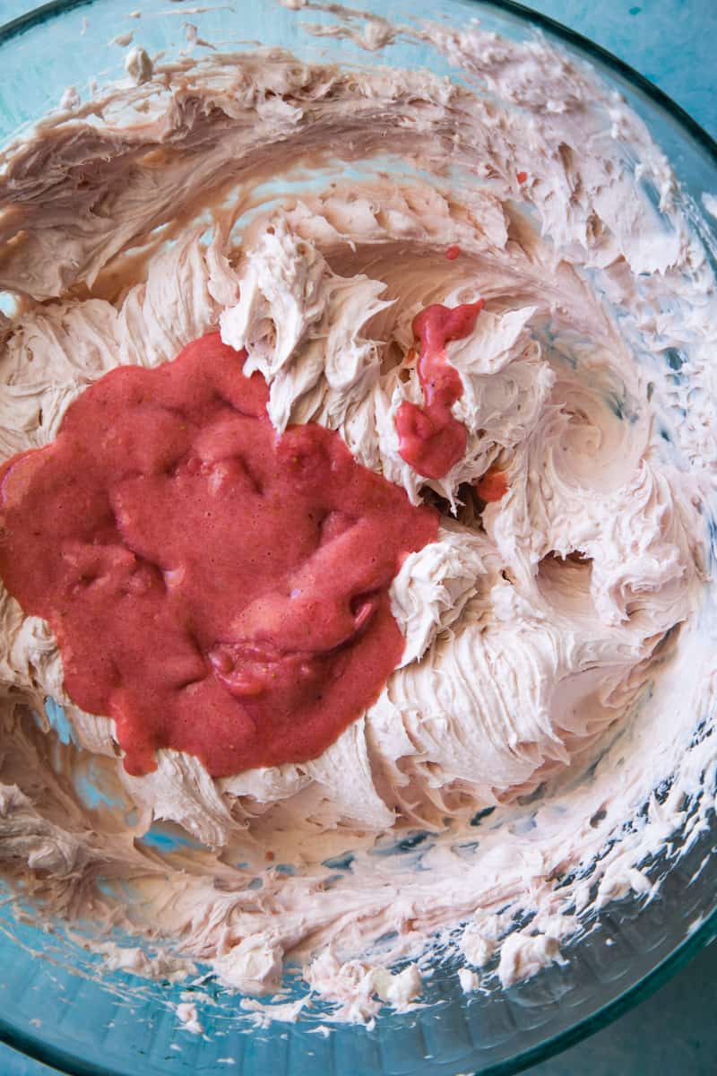 whipped cream cheese with strawberry puree added in a large glass bowl.