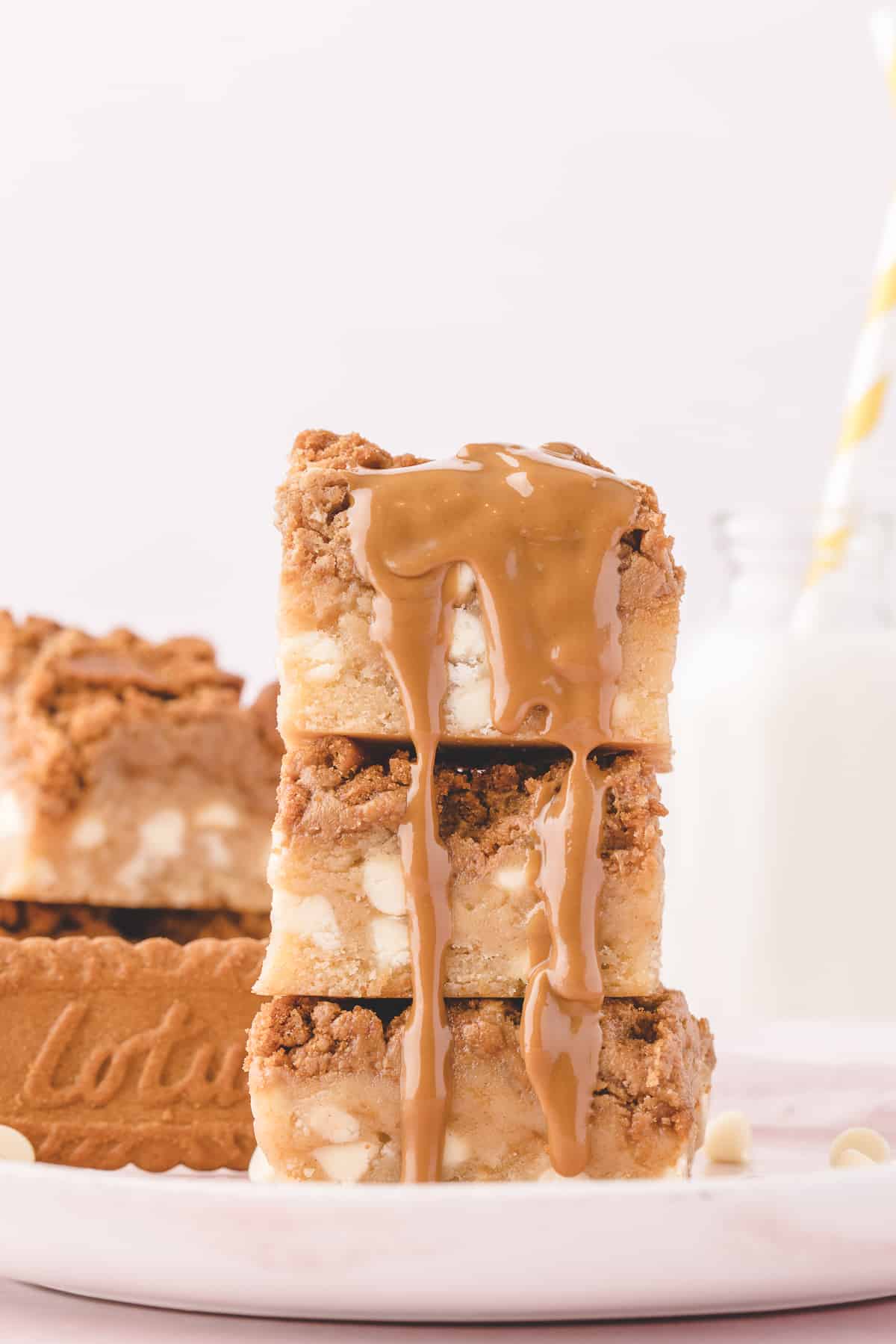 Stacked blondies on white plate with melted cookie butter spread dripping off one side. 
