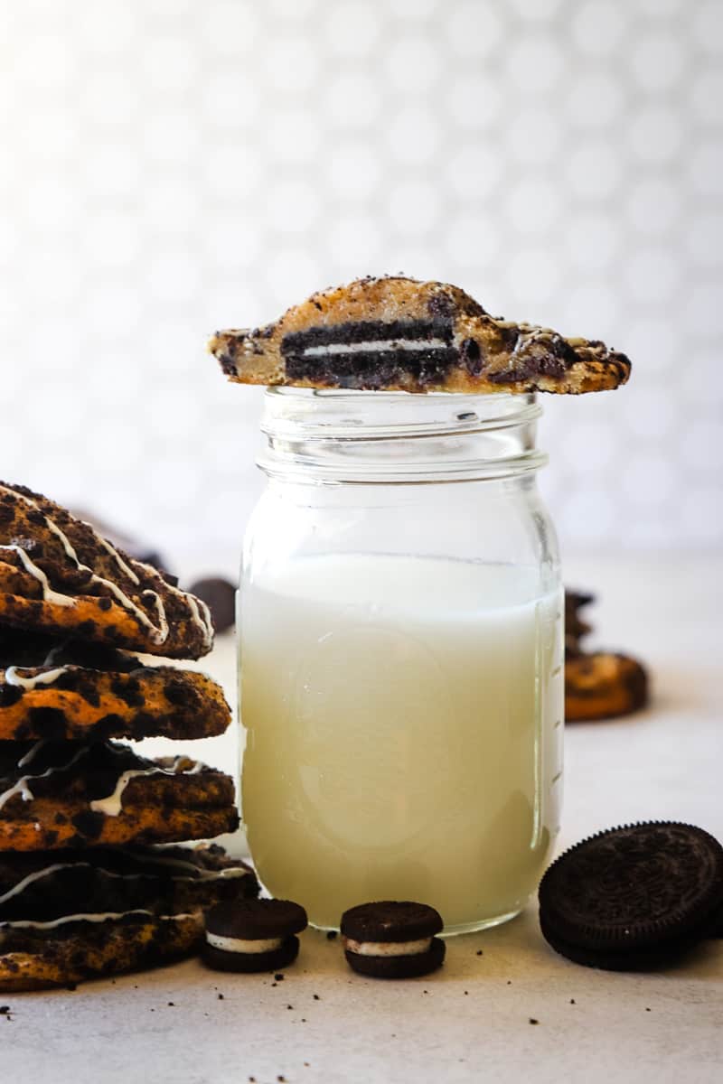 Mason jar filled with milk with half of cookie sitting on top of glass. 