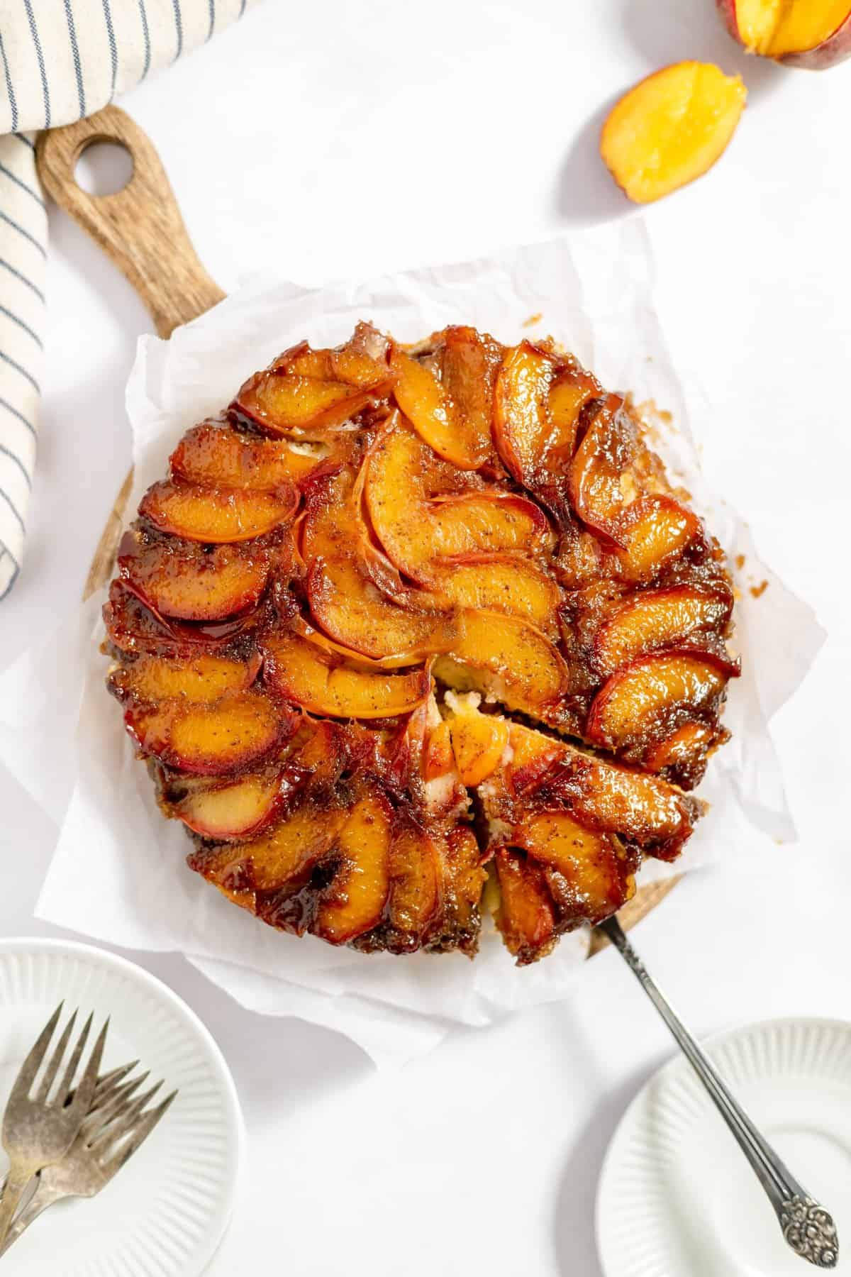 Whole peach upside cake with a serving spatula removing a slice.