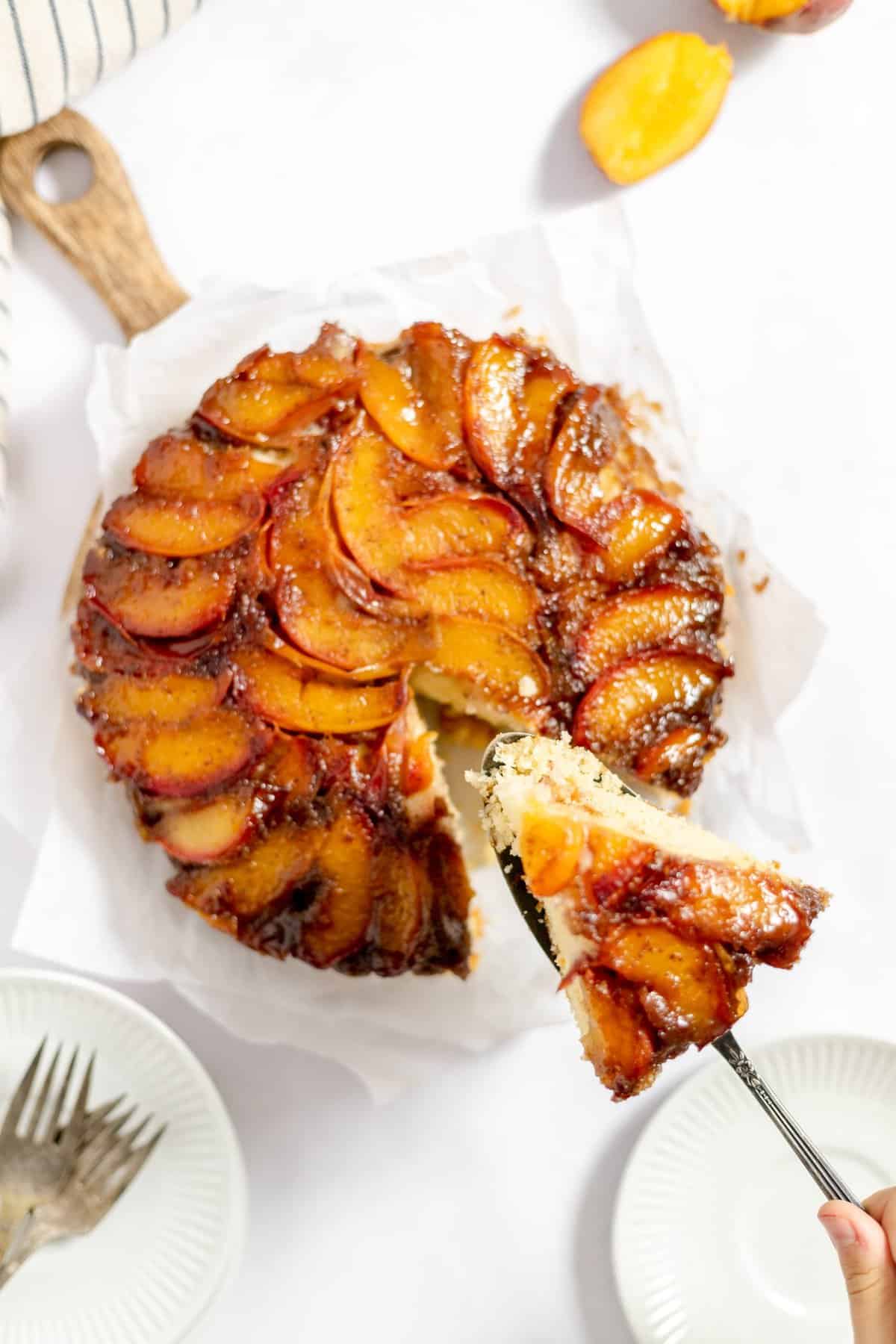 overhead shot of a whole peach cake with spatula removing a slice.