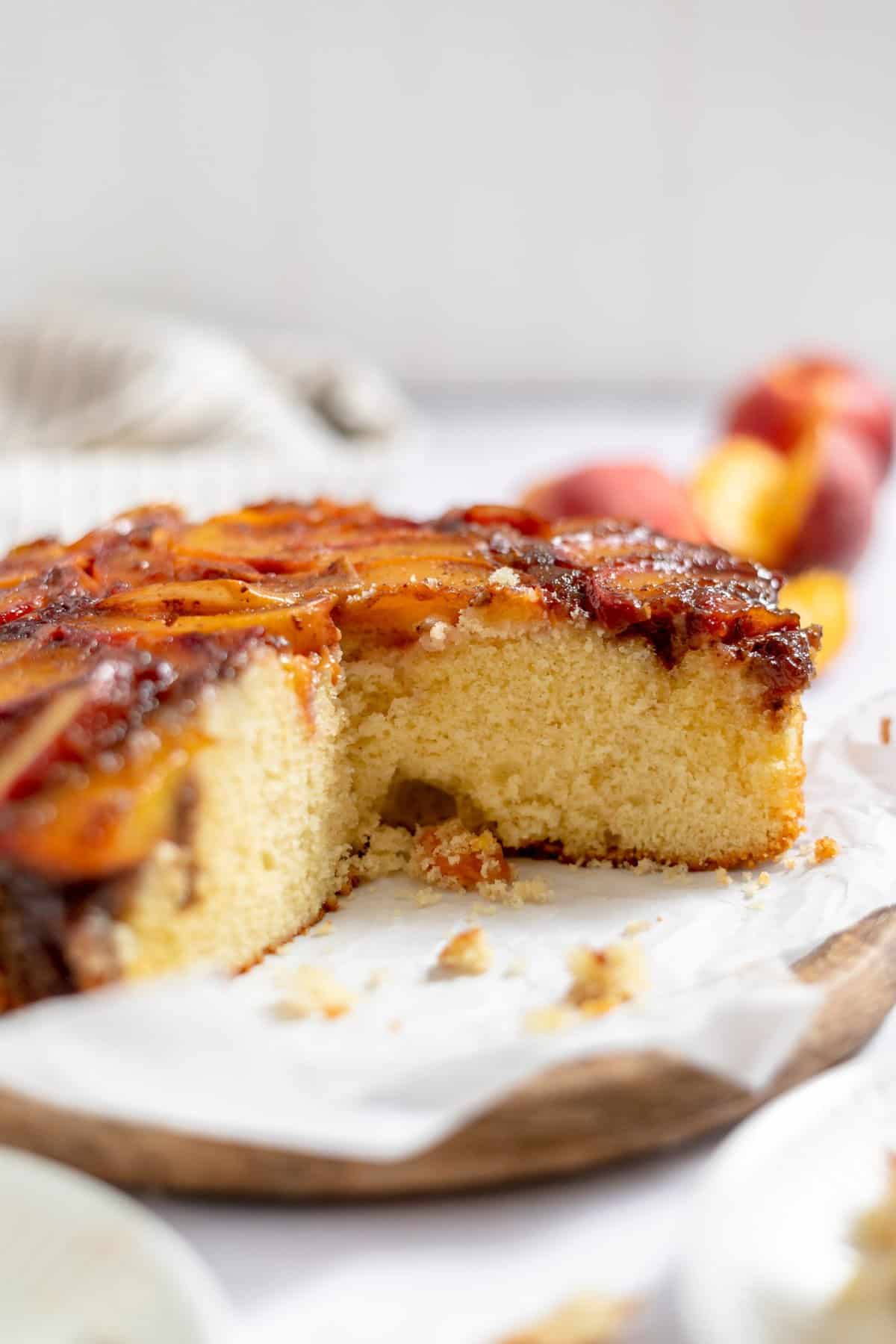 Shot of the inside of the cut peach upside down cake on wooden cutting board.