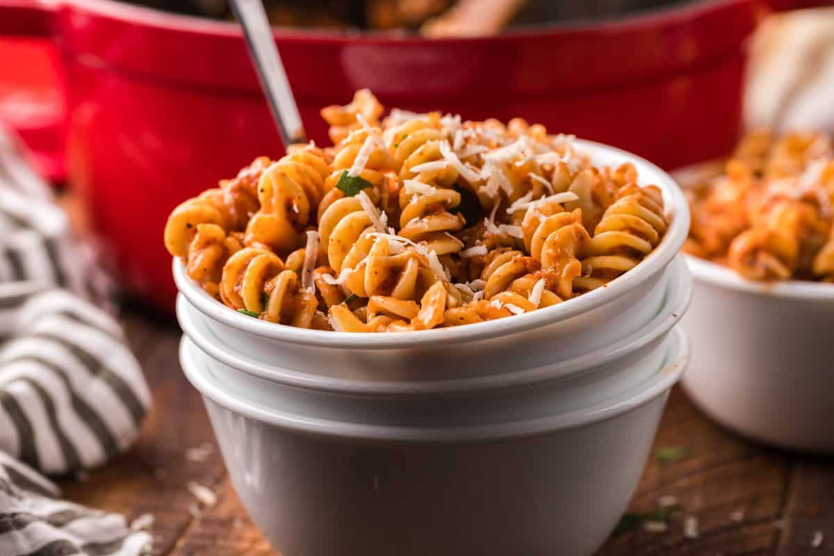 horizontal photo of white bowl filled with pasta and a spoon.