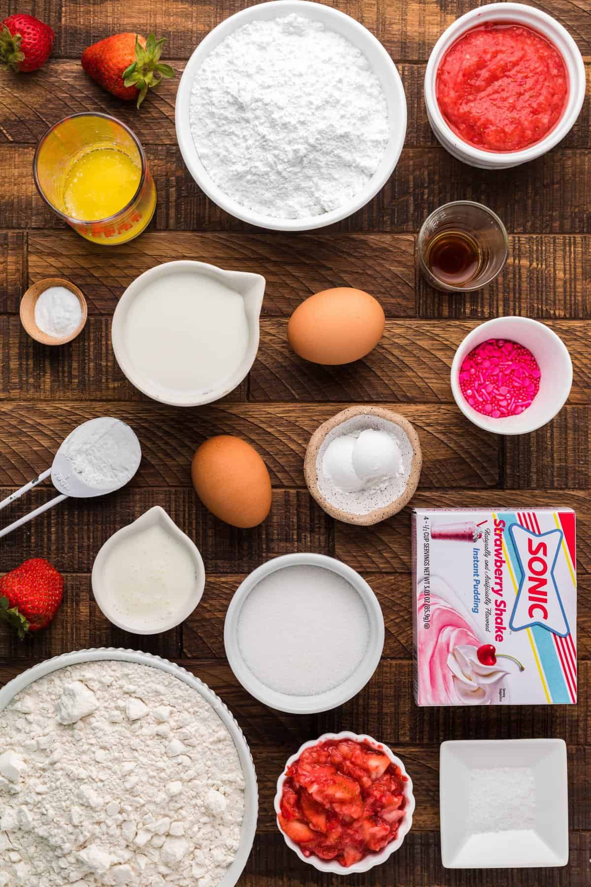 Ingredients to make the strawberry donuts on a wooden backdrop.