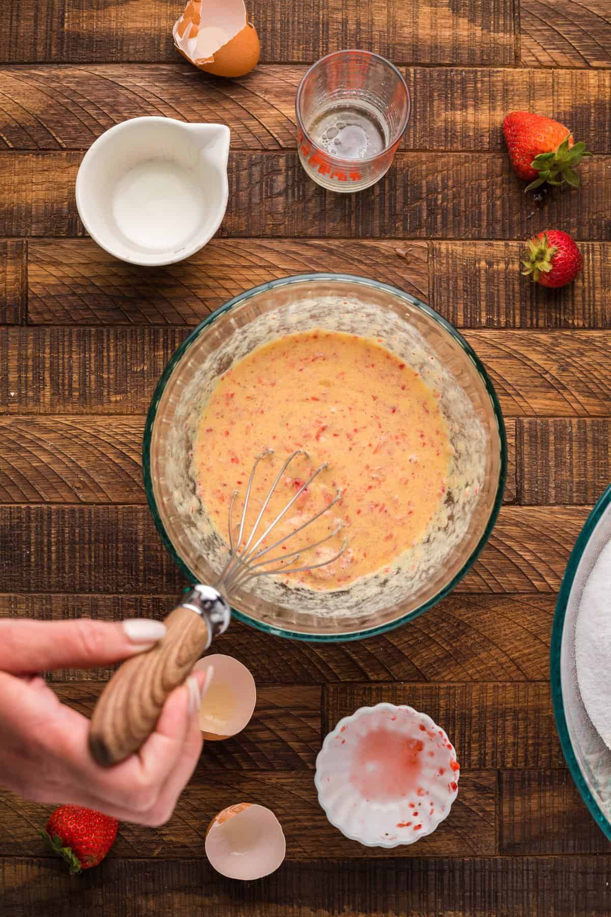 hand whisking together the strawberry donut batter.
