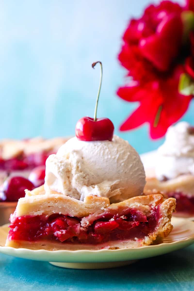 Up close photo of a slice of cherry slab pie with a scoop of vanilla ice cream on the top. 