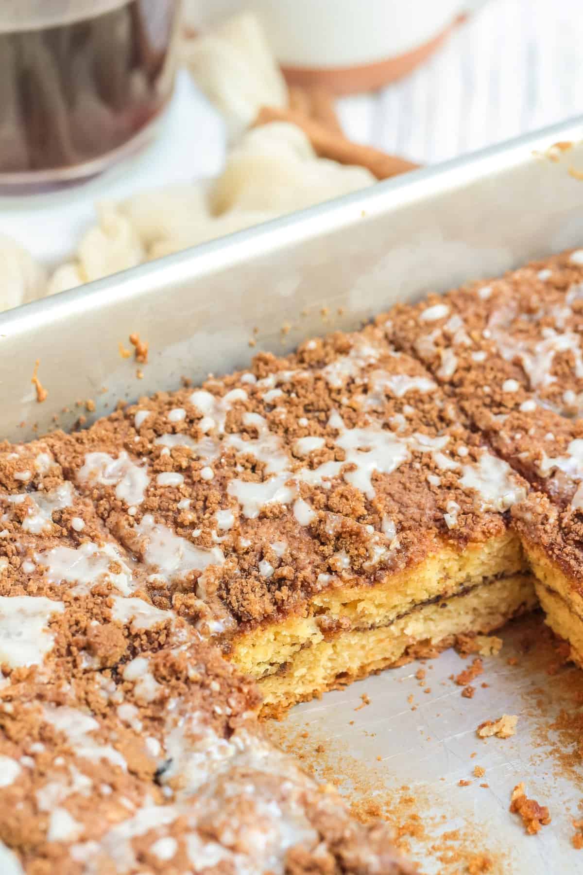 Metal plan with coffee cake with one slice removed from pan. 