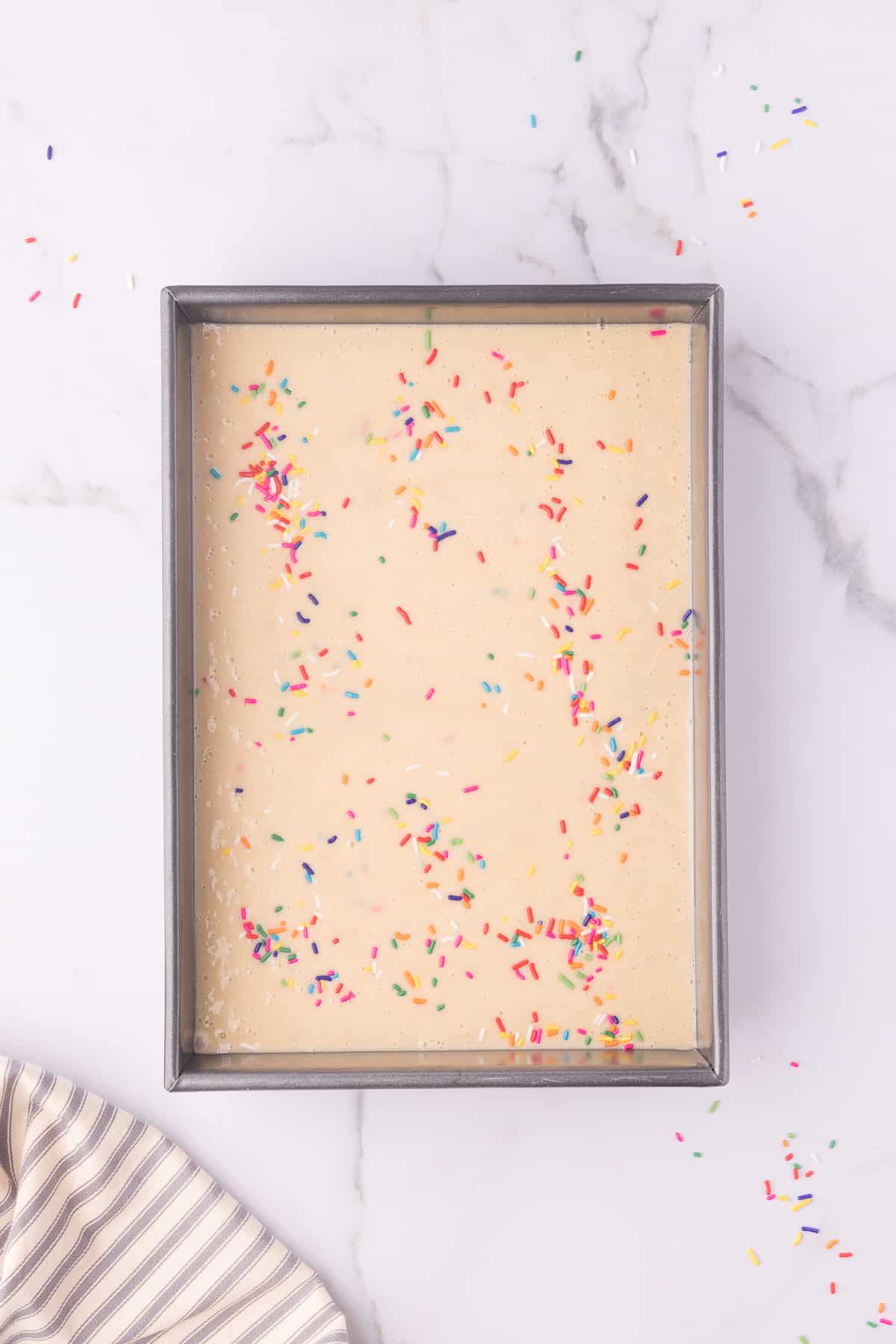 Large rectangle pan with funfetti batter on marble background. 