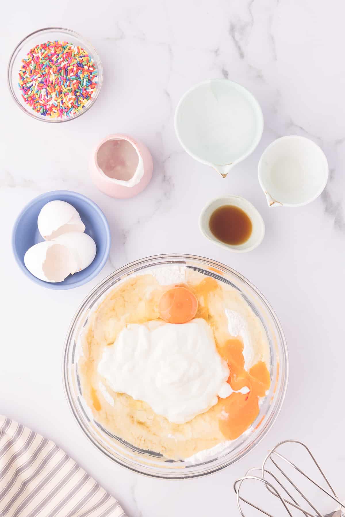 Glass bowl with eggs and flour mixture to make the vanilla sheet cake batter. 