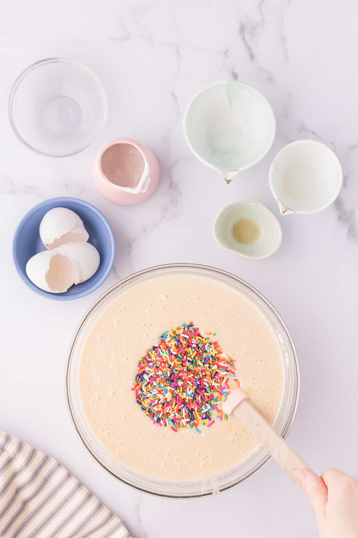 Hand stirring in the sprinkles to the vanilla batter in large glass bowl. 