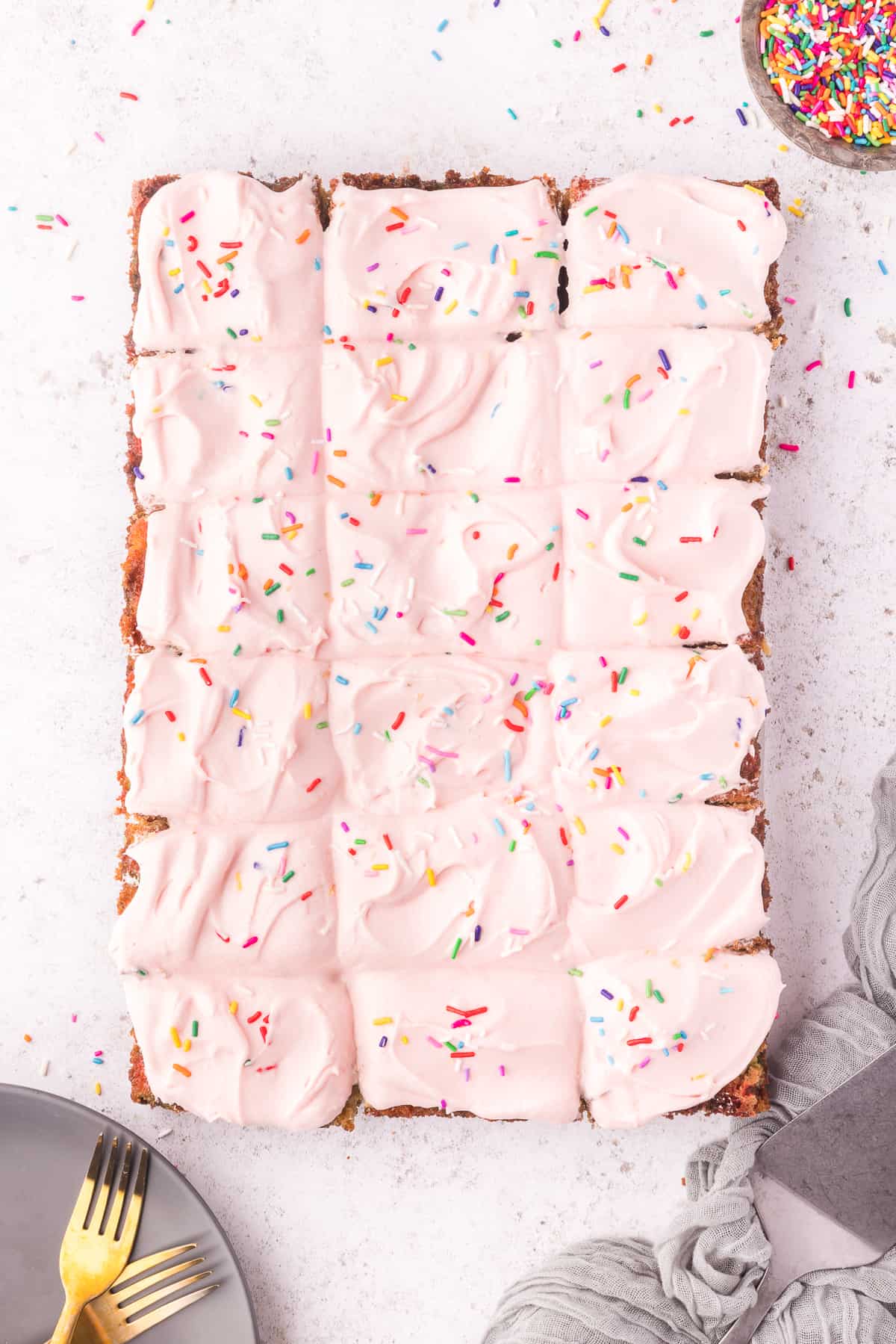 Overhead shot of the entire sheet cake with pink frosting on white background. 