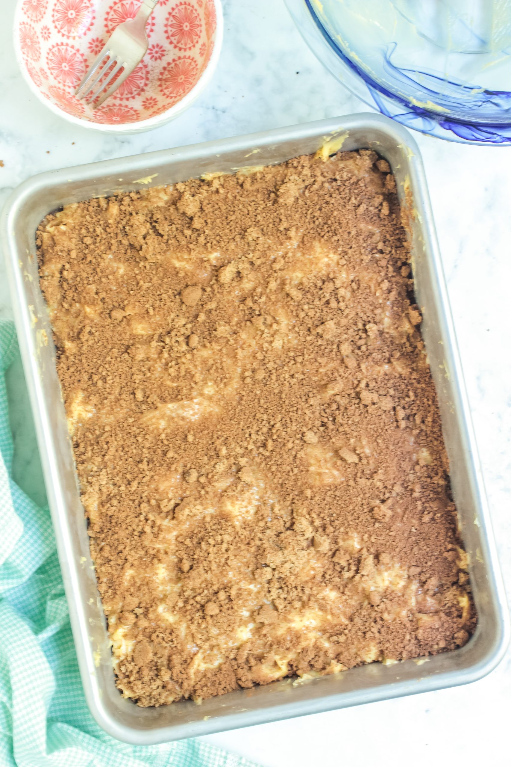 Overhead shot of the unbaked coffee cake with crumb topping in rectangle pan. 